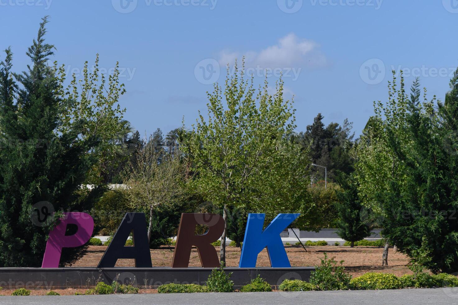 Colorful park letters stand out against green trees and a bright blue sky on a sunny day in a lively outdoor environment photo