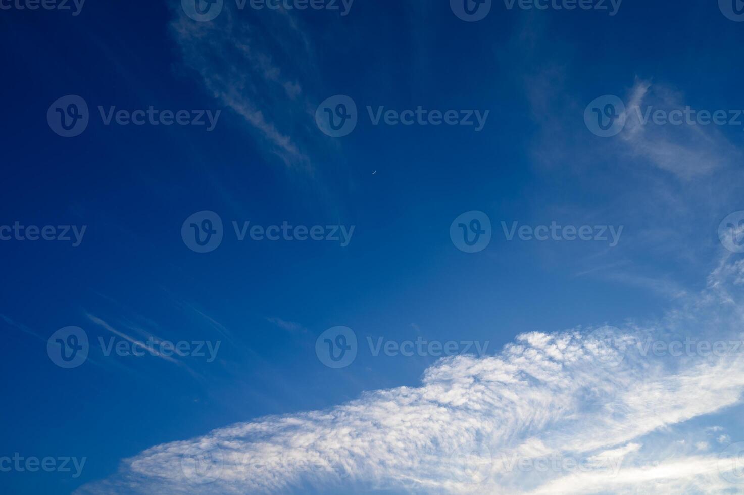 Expansive azure sky adorned with wispy clouds at midday revealing a atmosphere photo