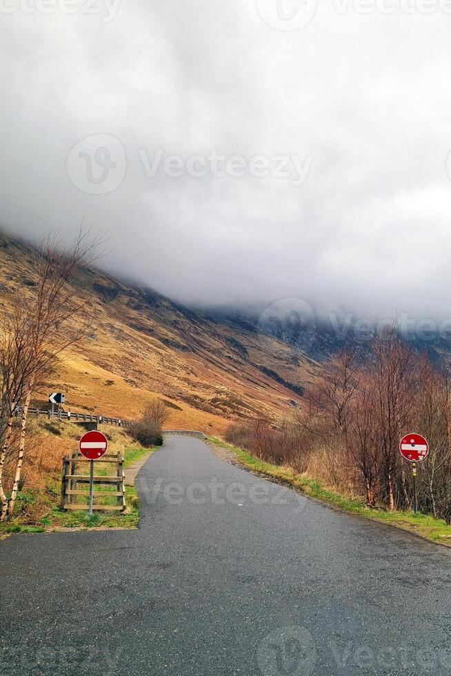 Serene Mountain Road with Cloudy Skies in a Scenic Landscape photo