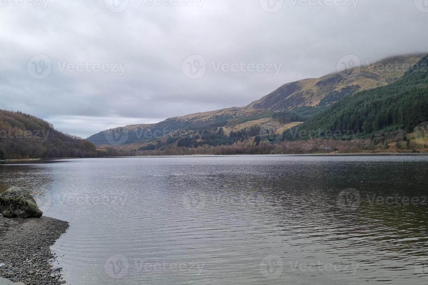 Serene Mountain Lake Scene with Overcast Skies and Forested Hills photo