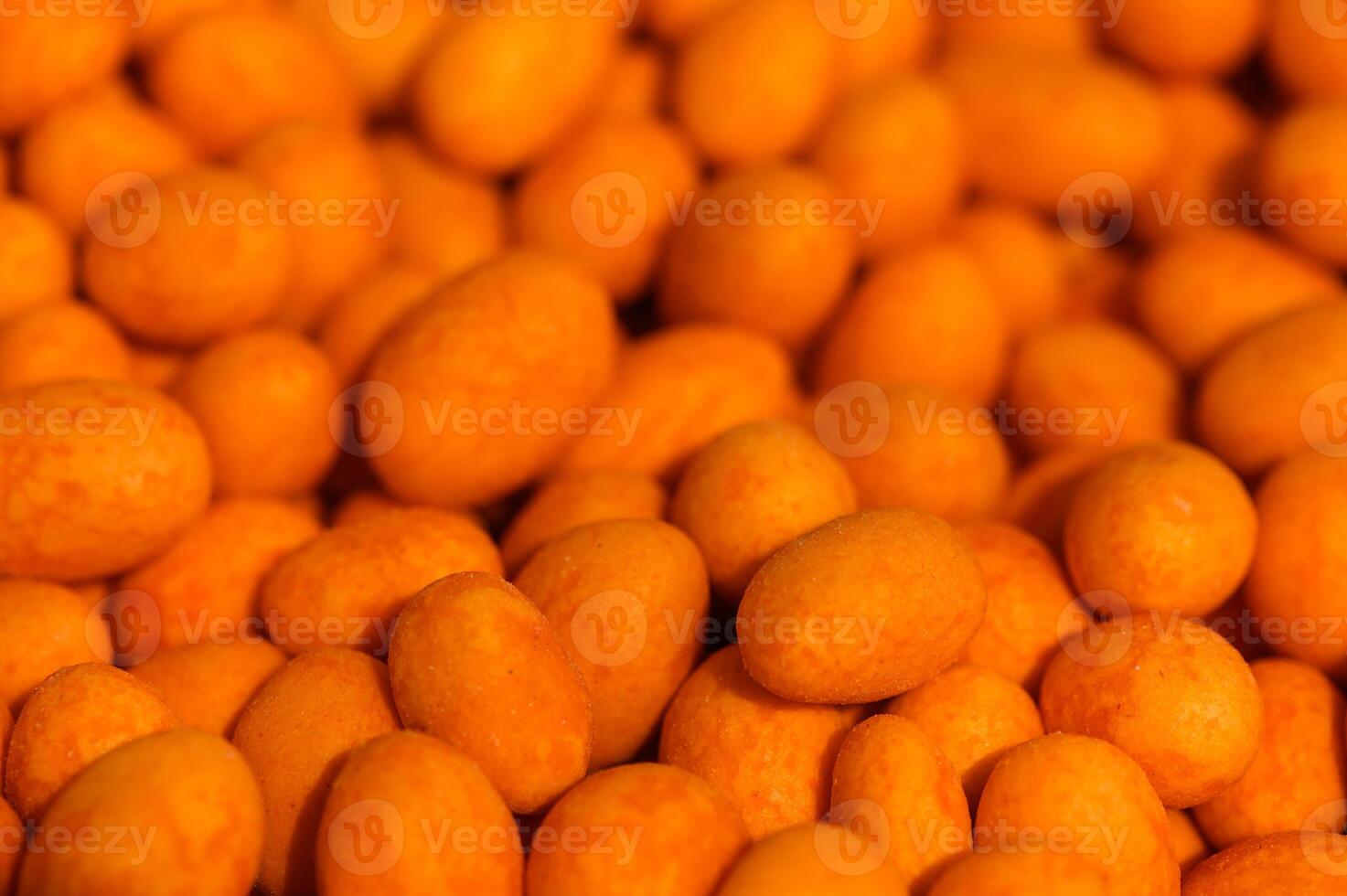 Vibrant orange candies glisten under soft light, tempting sweet lovers in a bustling market photo