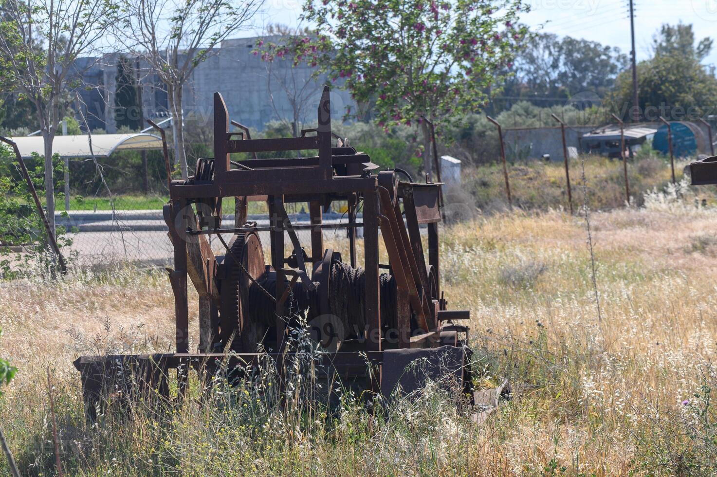Forgotten machinery rests silently in an overgrown field under the bright midday sun photo