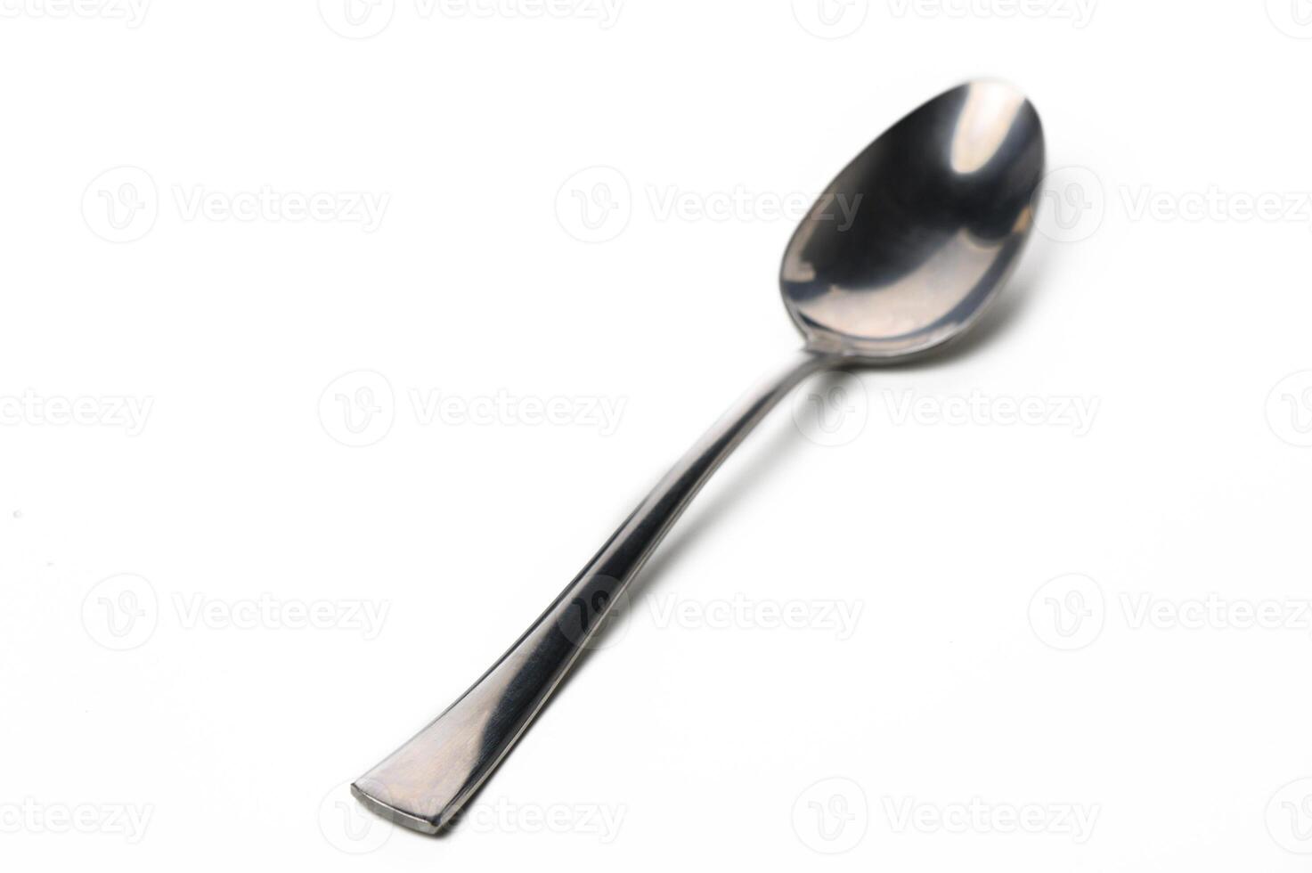 Elegant stainless steel spoon resting on white surface with a subtle shine captured in soft light photo