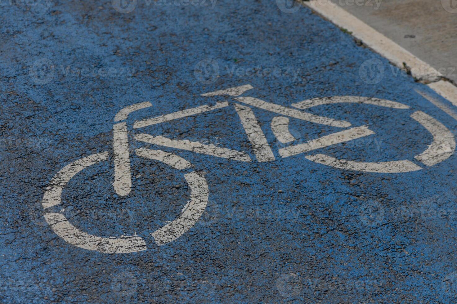 Bicycle lane marking on a vibrant blue pavement indicating safe space for cyclists in an urban setting photo