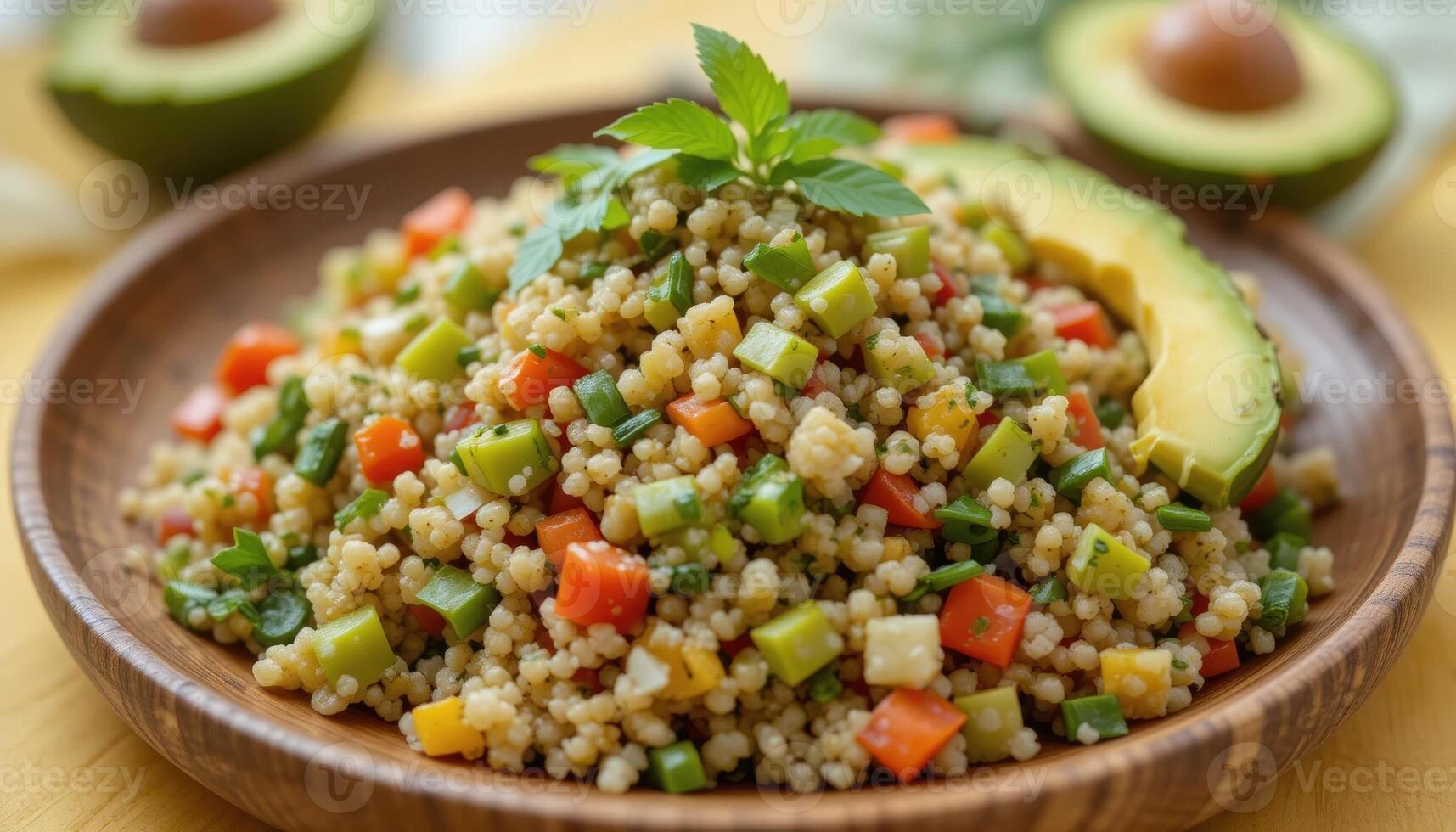 There is a delicious couscous dish on a wooden plate, decorated with cubes of bright vegetables, herbs and slices of avocado. The marble-topped table complements the fresh and healthy look of photo