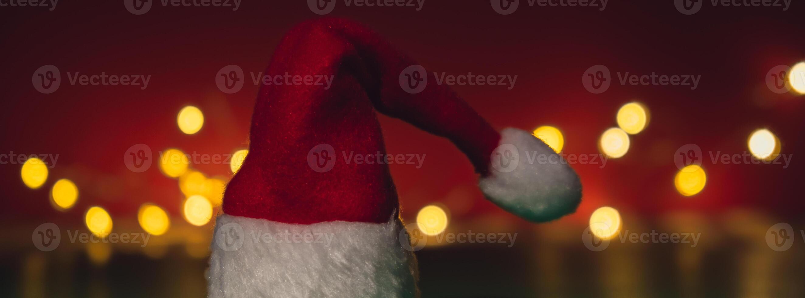 Santa hat on isometric green red background. Defocused lights on backdrop Copy space for your text. Mock up for advertisement. Holiday Christmas composition. Minimalistic greeting card. Creative photo