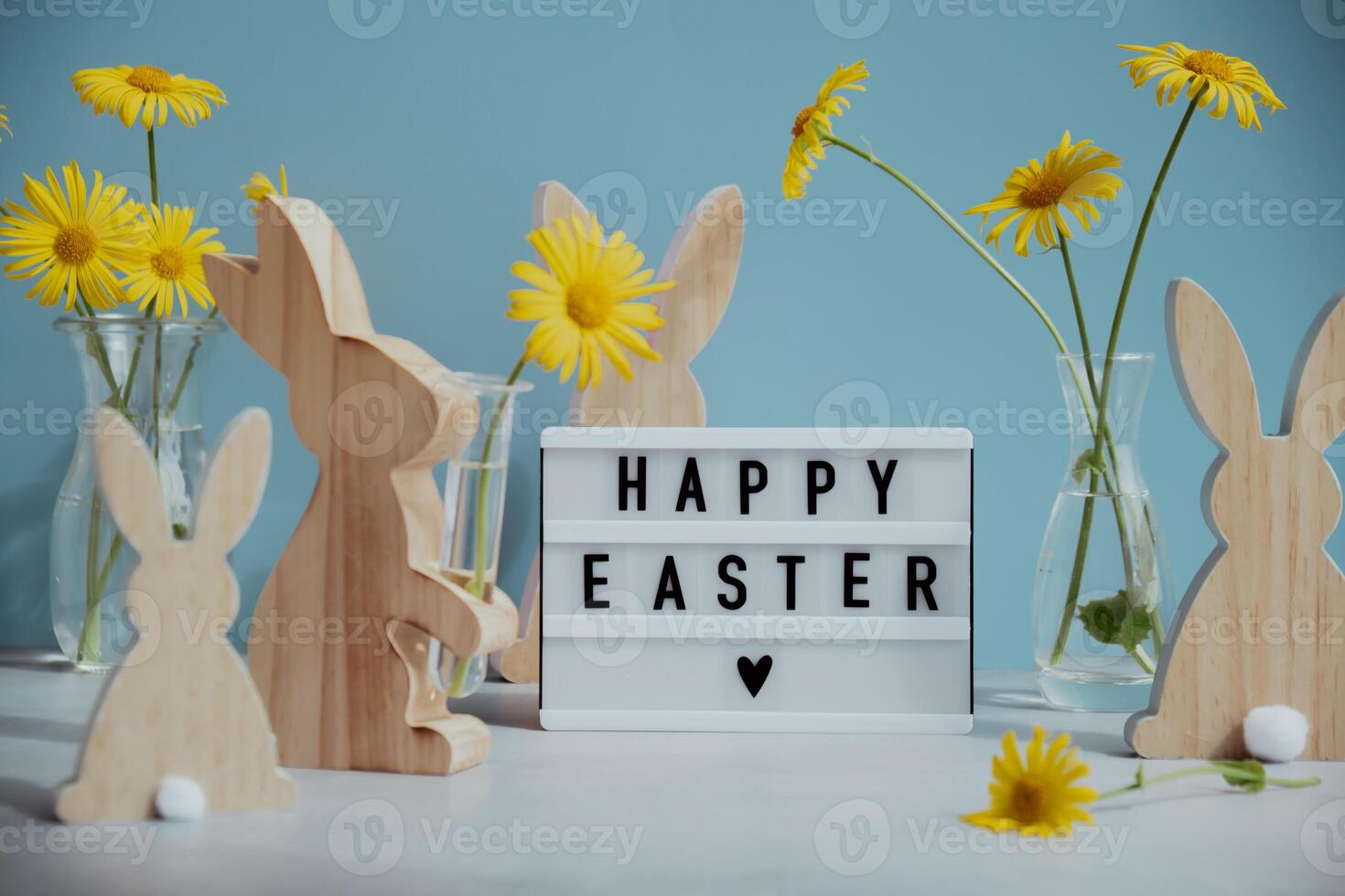 Phrase HAPPY EASTER traditional greeting to christian holiday. Festive mood composition with bunnies and yellow flowers on pastel blue background. Sustainable decorations photo