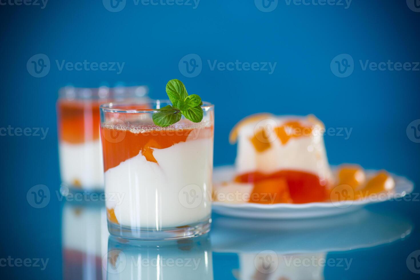 Portioned jelly dessert in a glass with yogurt cream and fruits photo