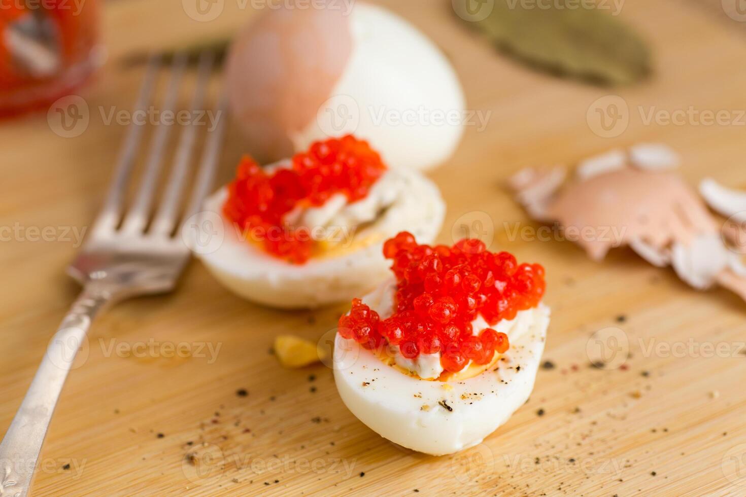 Boiled egg halves with red caviar on a wooden board photo
