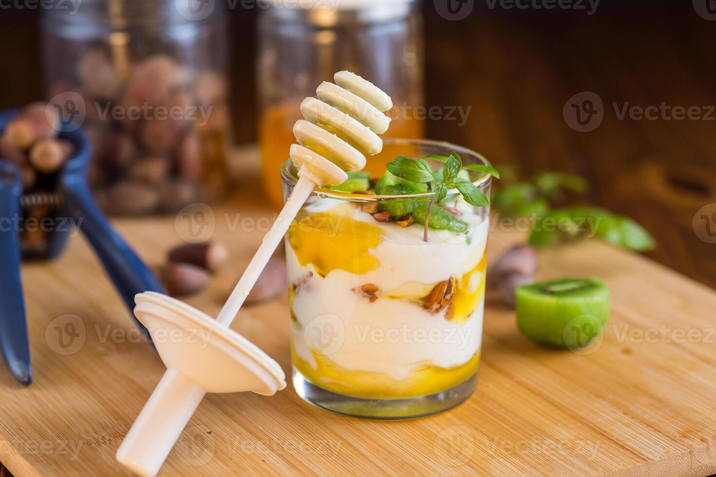 Simple breakfast.homemade yogurt with kiwi, honey and nuts in a glass on a wooden table photo