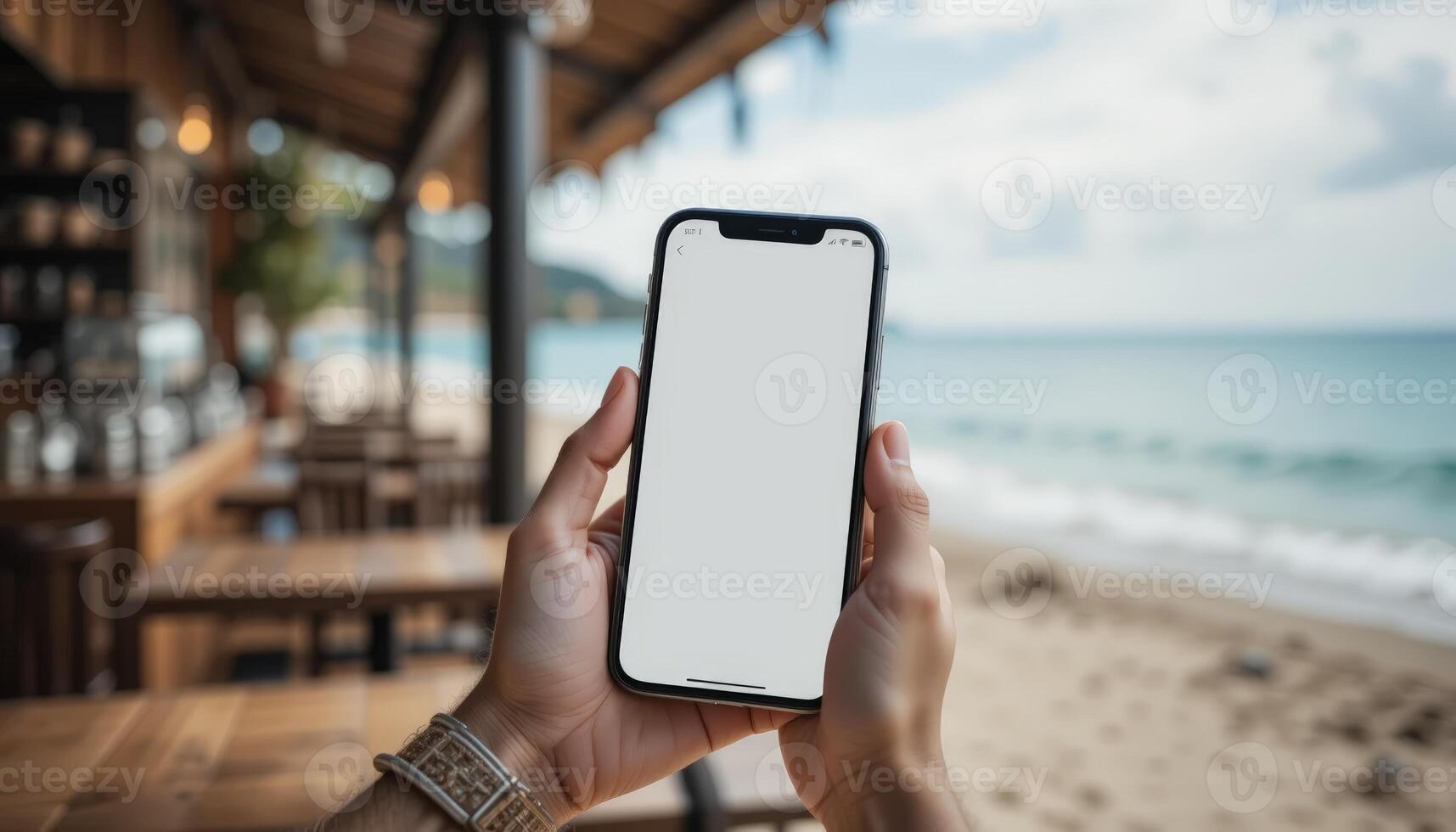 A close-up of a person holding a smartphone with a blank screen against a beautiful beach backdrop, perfect for travel-related content. photo