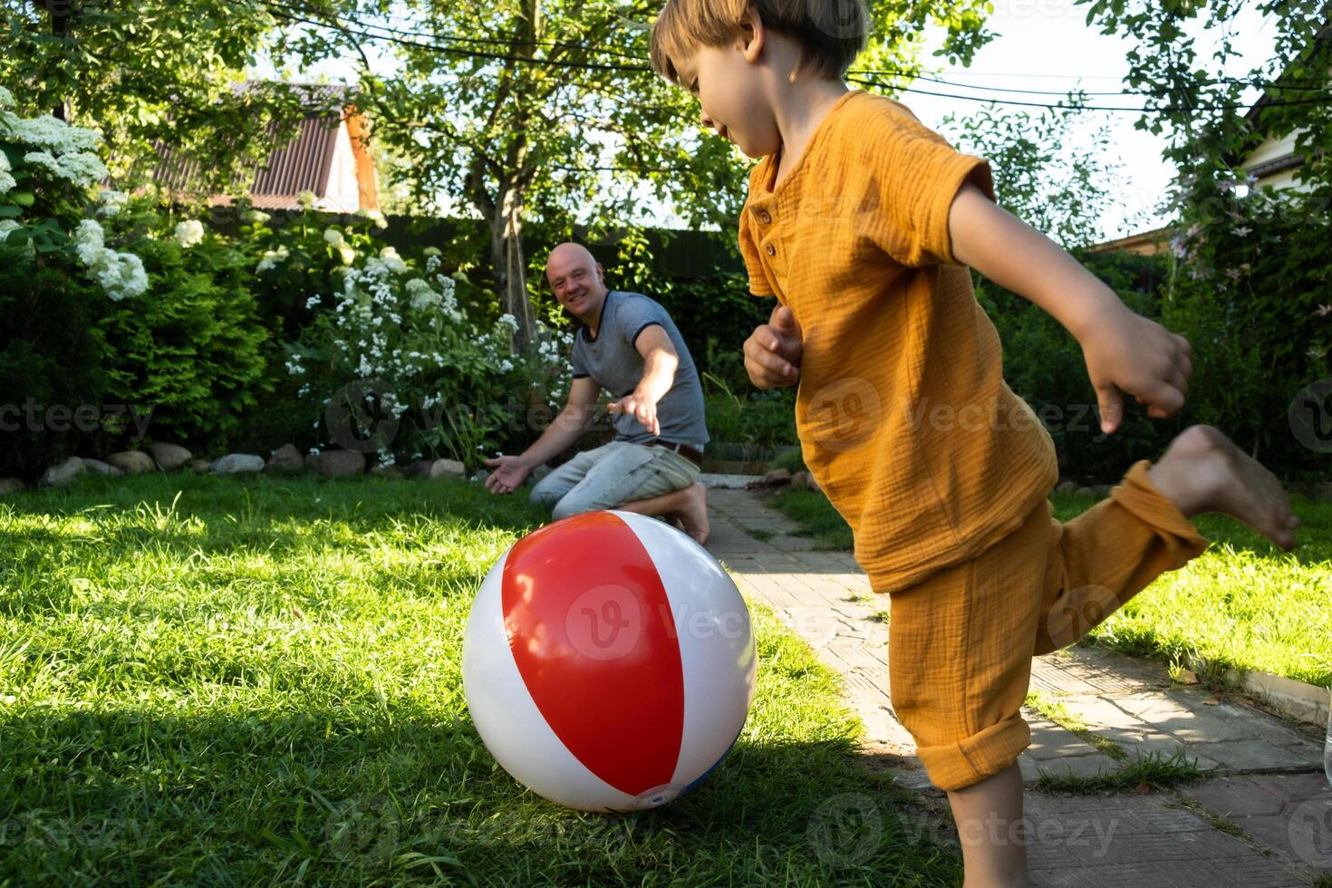 Summer vibes, family lawn games. Father and small child having fun playing with beach ball in backyard. photo