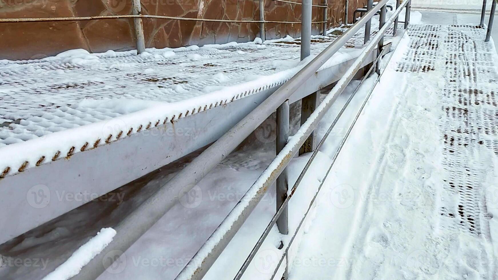Close-up of a ramp with meta railings, covered with snow, for baby strollers and handicapped accessibility. photo