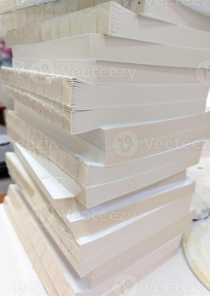 A stack of white paper books sitting on top of a table photo