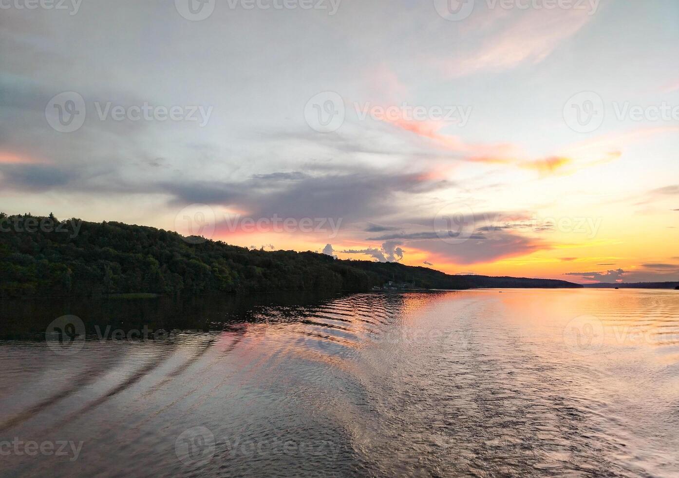Doldrums and ripples from the waves on the surface of the water from a ship sailing away on a pink sunset, river trip photo