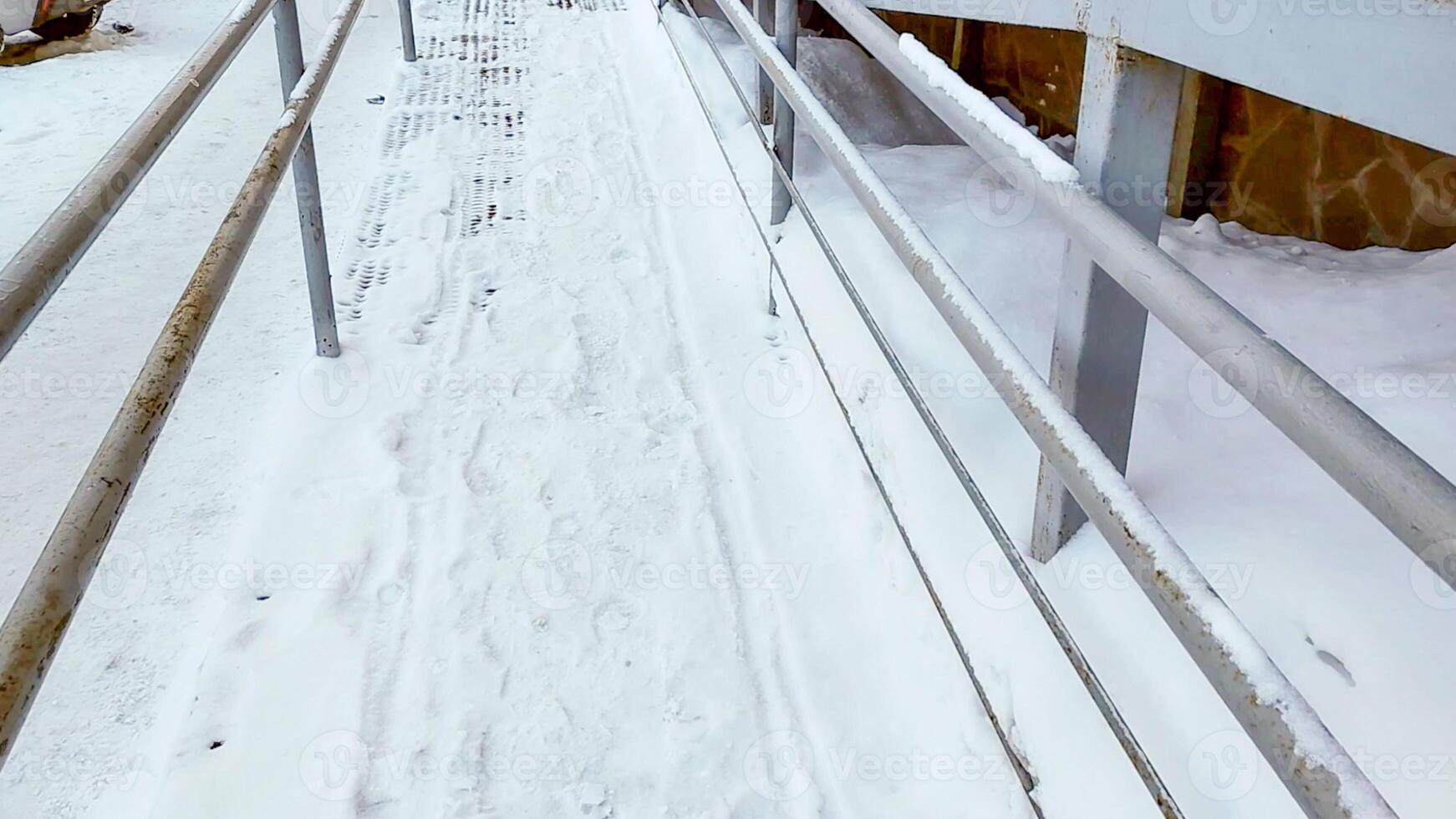 Close-up of a ramp with metal railings, covered with snow, for baby strollers and handicapped accessibility photo