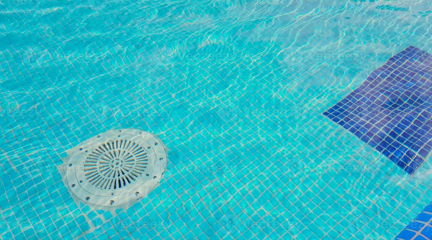 Cleaning of the drain valve filter at the bottom of the swimming pool, movement of clear water, top view. photo