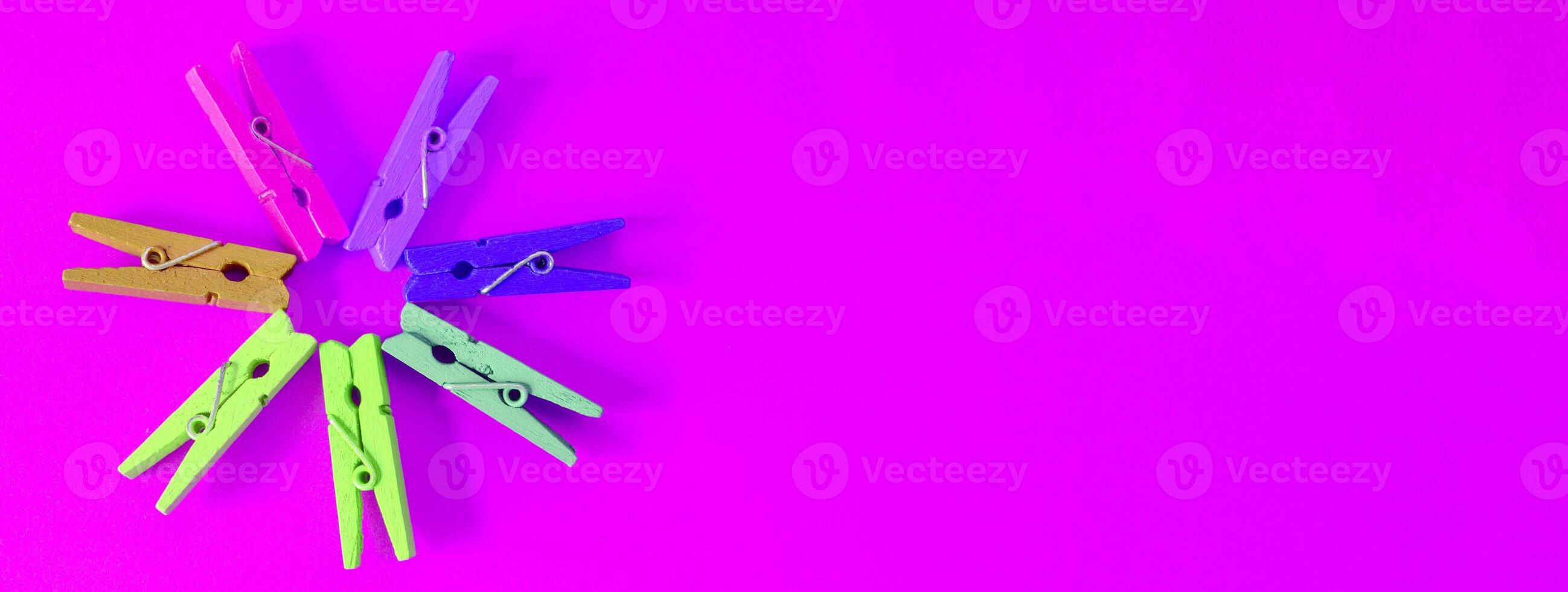 Colorful clothes pegs on a pink background photo