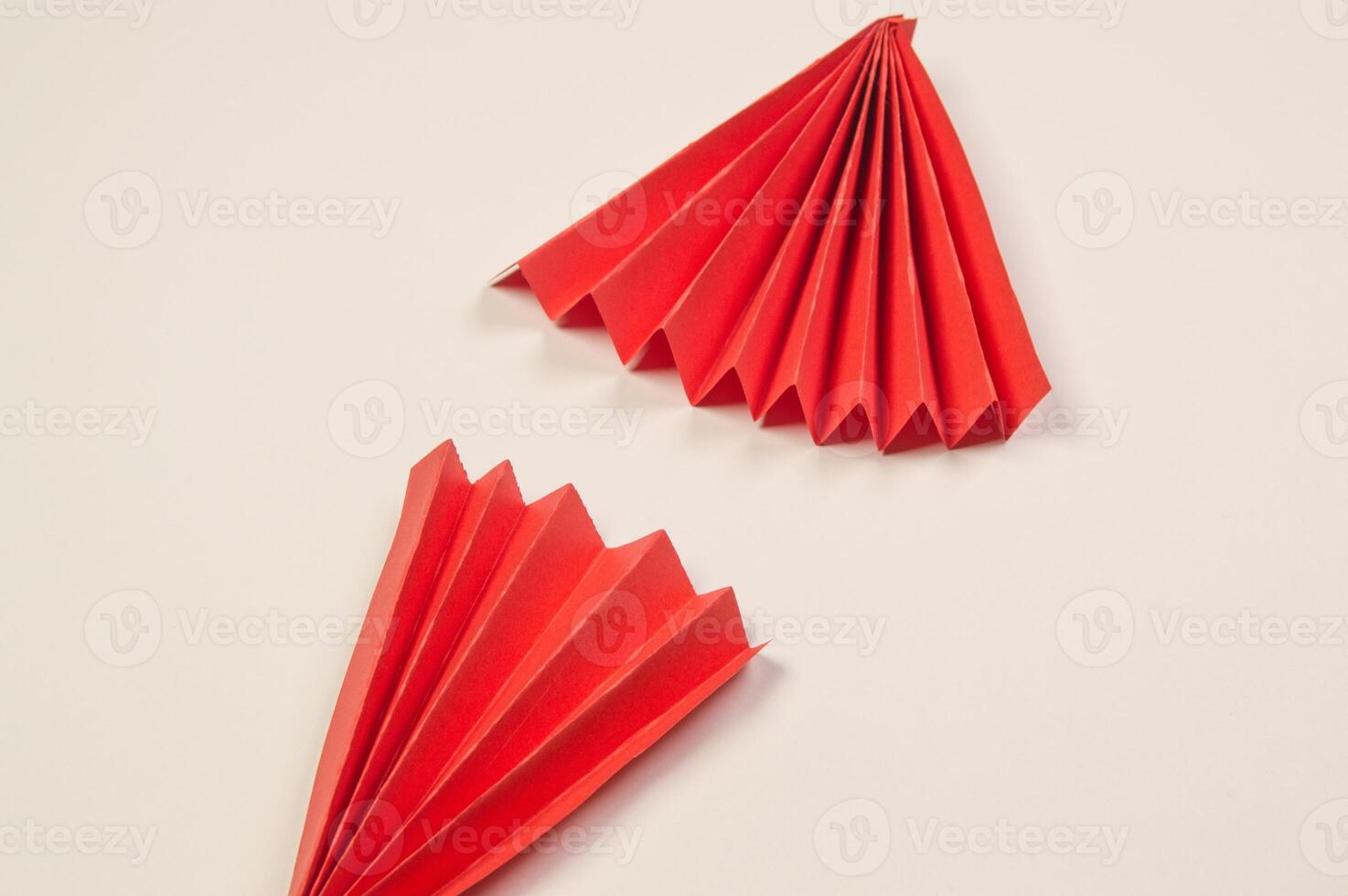 Two red origami triangles on a white surface photo
