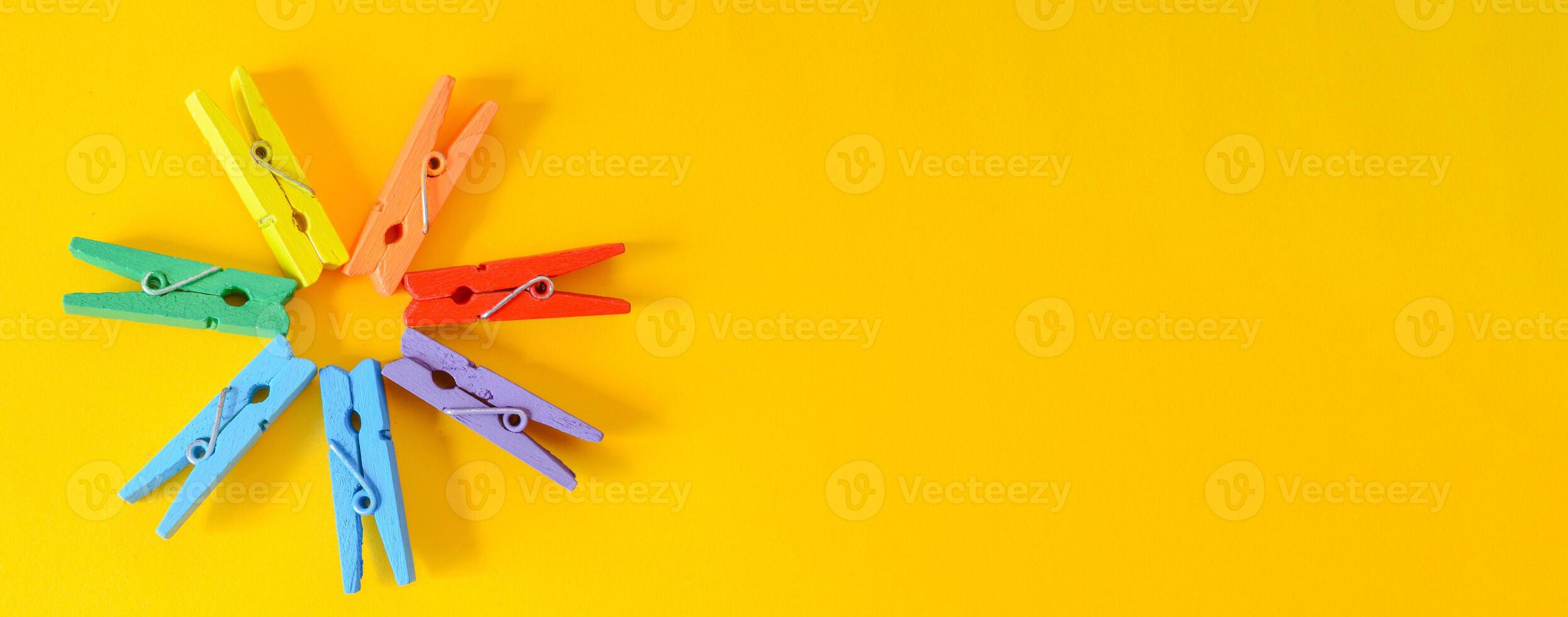 Colorful clothes pegs on yellow background. photo