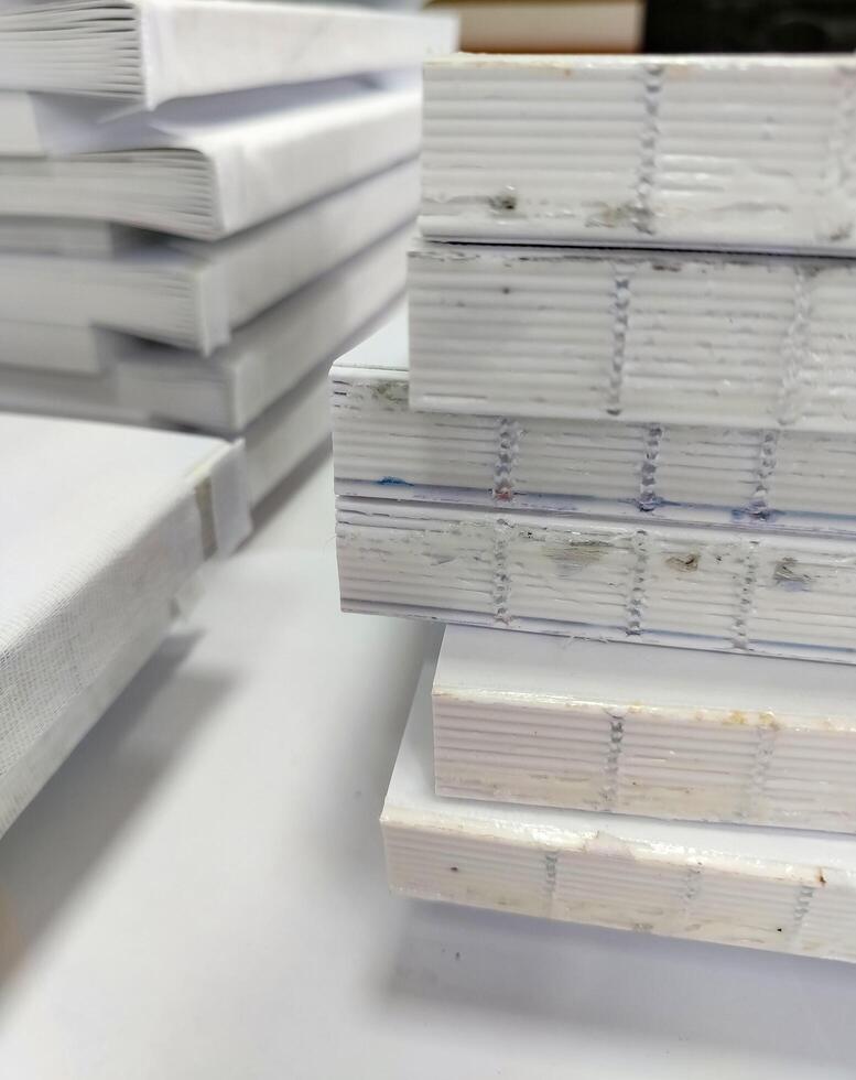 Close-up, a stack of glued book blocks prepared for binding in a printing house, vertical photo