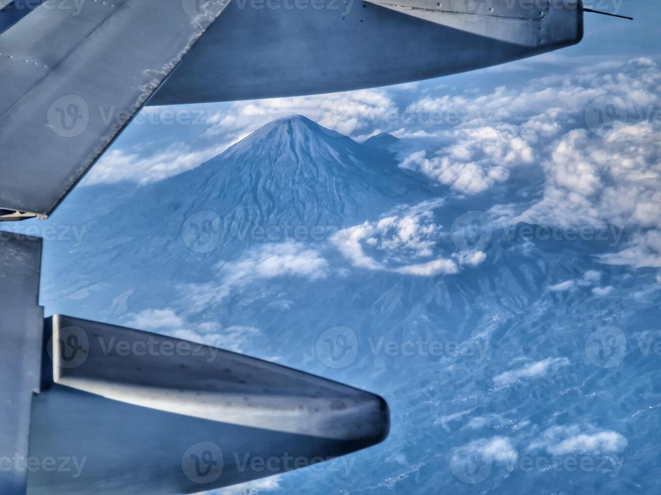 Mountain View From Airplane Window with Clouds and Blue Sky photo
