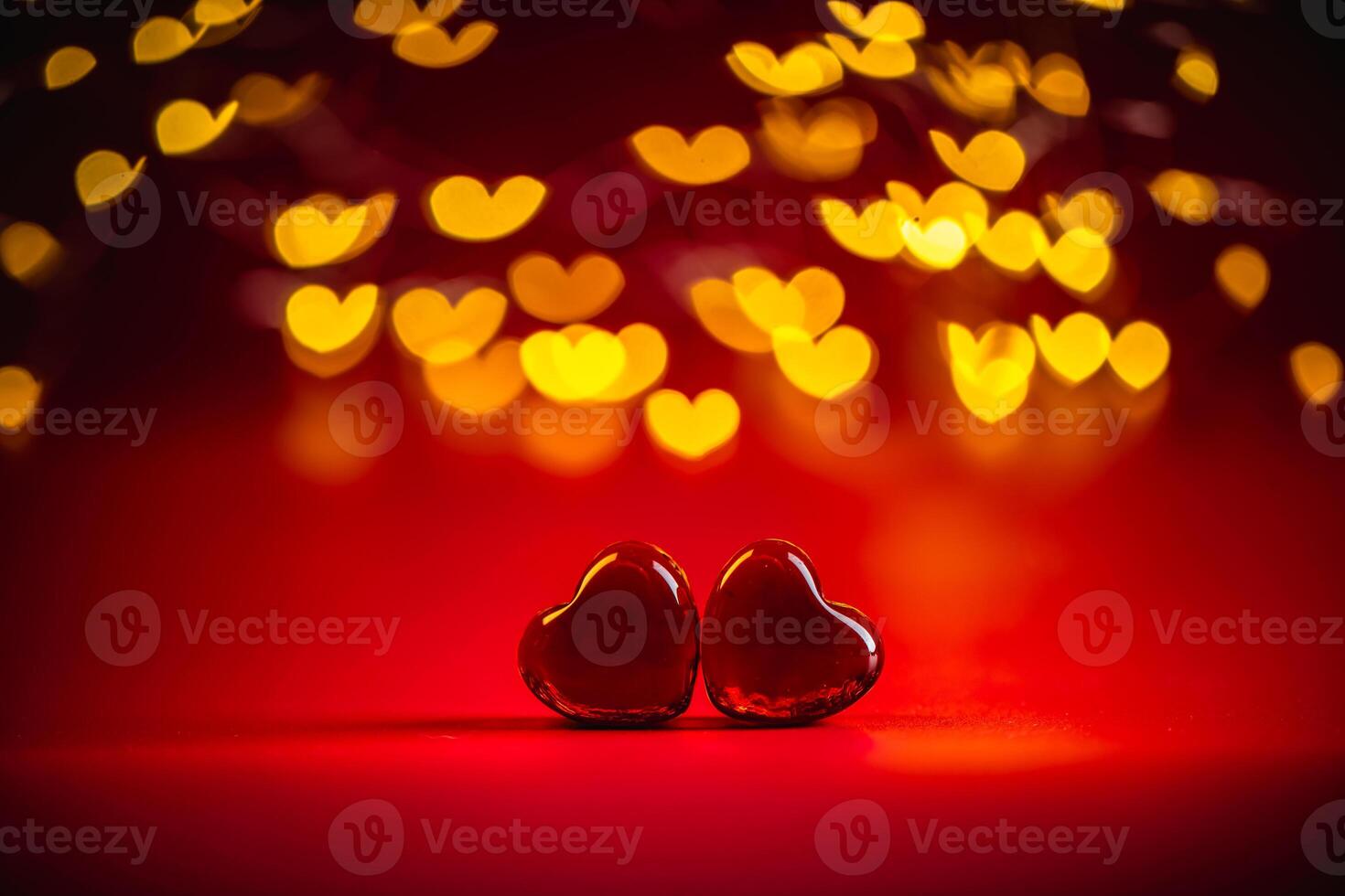 Two red heart-shaped objects rest against a vibrant red background, surrounded by a dreamy bokeh of glowing heart lights, creating a romantic and enchanting valentine's day theme photo