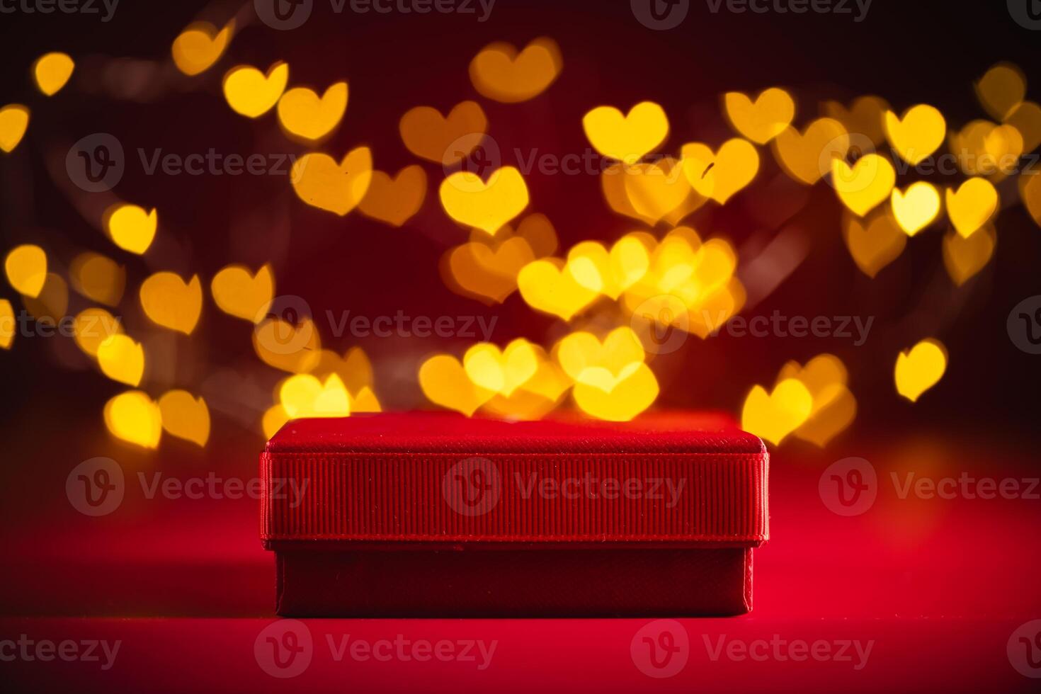 Red gift box adorned with a ribbon, set against a backdrop of glowing heart-shaped bokeh lights, creating a romantic atmosphere ideal for valentine's day celebrations photo