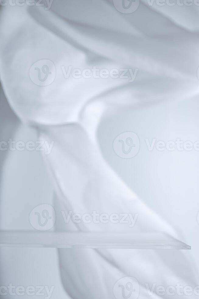 Empty glass shelf with flowing white cloth backdrop creating a soft, elegant setting, ideal for showcasing products or creating a minimalist aesthetic photo