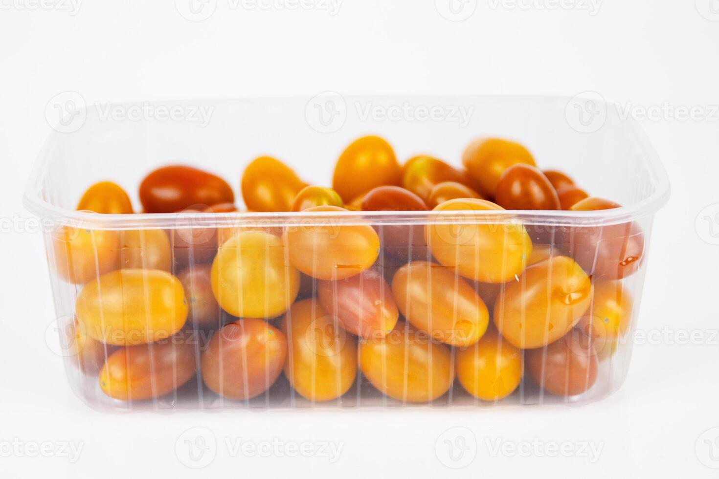 Plastic container of fresh yellow and orange cherry tomatoes isolated on white background. Tomatoes in transparent pack, perfect for grocery, retail, and food market visual content. Copy space 03 photo