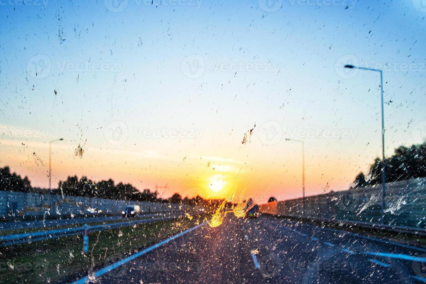 Highway view at sunset through a dirty windshield, emphasizing road safety and the challenges of visibility while driving on long journeys. Transportation, logistics, road traffic. Copy space 03 photo