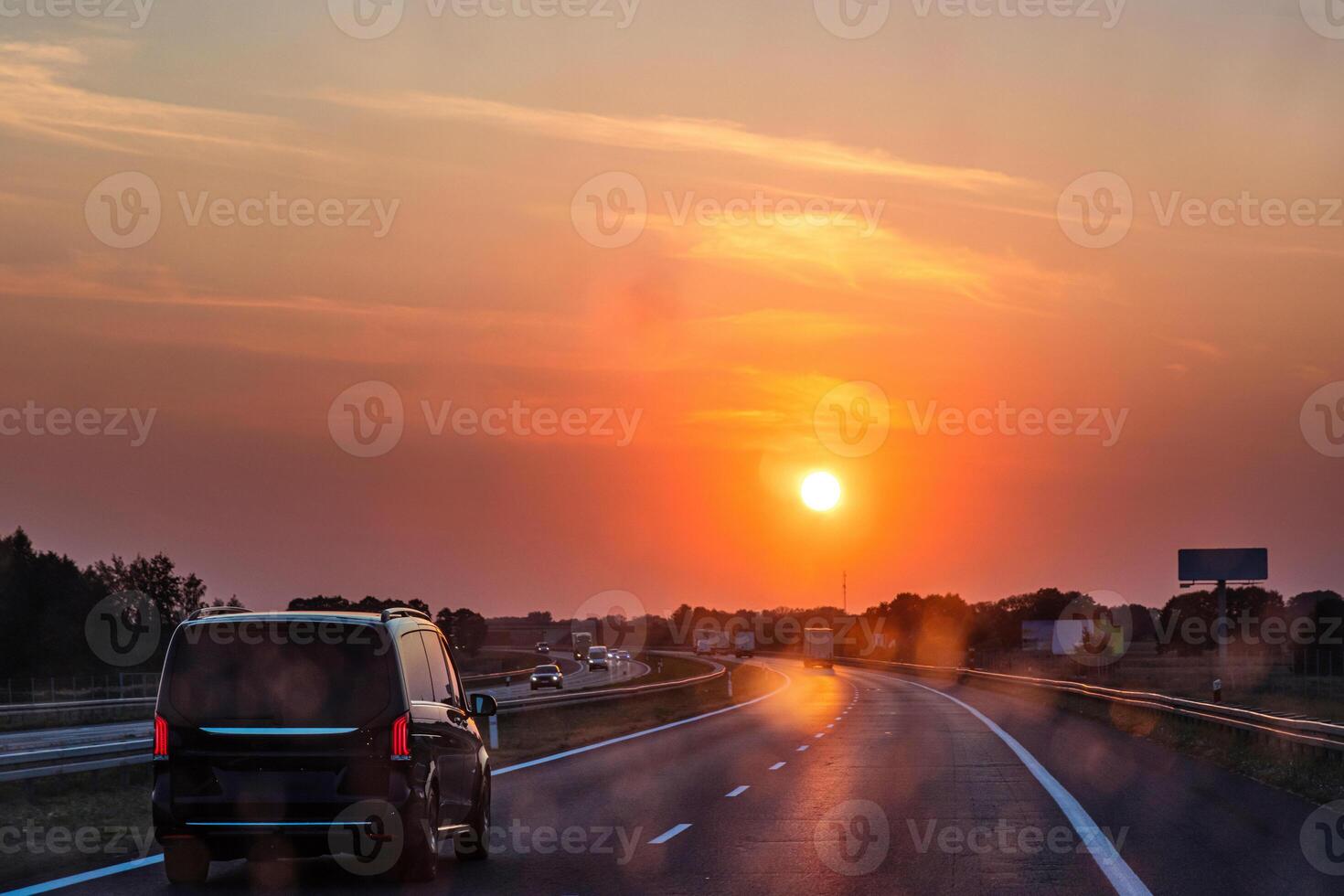 Scenic highway at sunset with minivan and cars and trucks driving through a dirty windshield. Concept of travel, transportation, freedom and the beauty of evening skies on the open road. 08 photo
