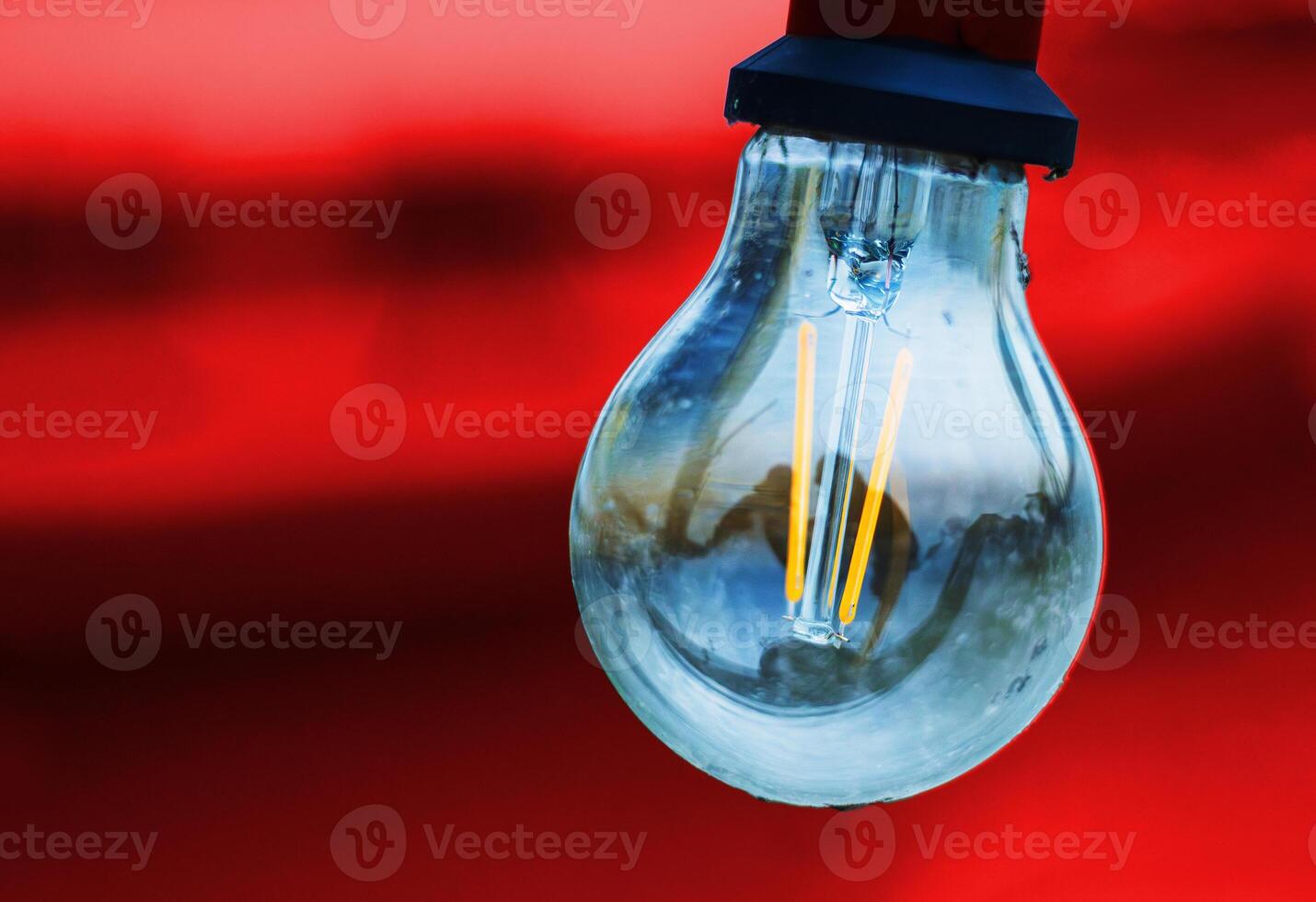 Glass bulb with socket on an red black background. Abstract concept image of colorful light lamp glowing against orange tones. innovation, technology, futuristic concept. Copy space photo
