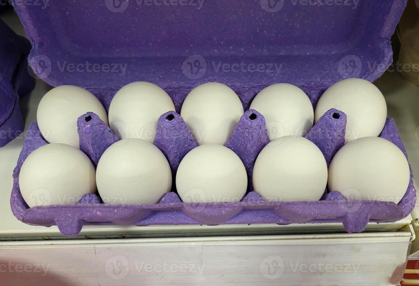 A lilac open egg carton with white eggs. Fresh organic chicken eggs in a container photo