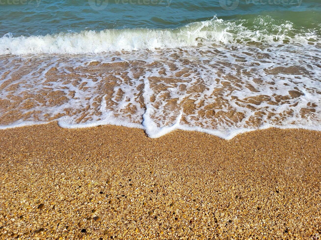 The concept of recreation. Beautiful azure sea with white foam and a beach on a clear sunny day photo