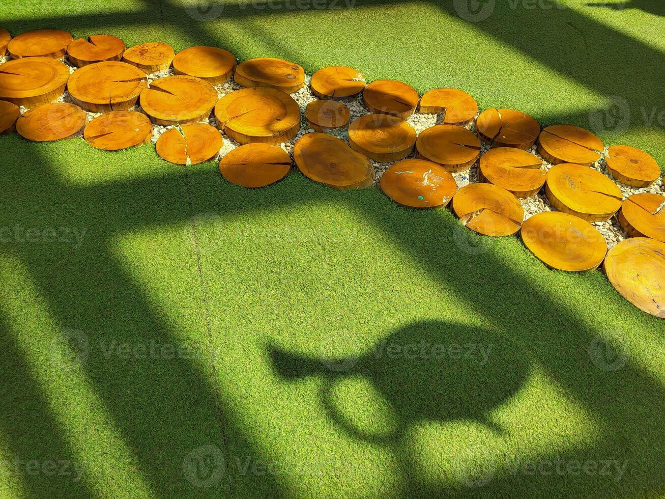 artificial green grass and round wooden sections with window shadows photo