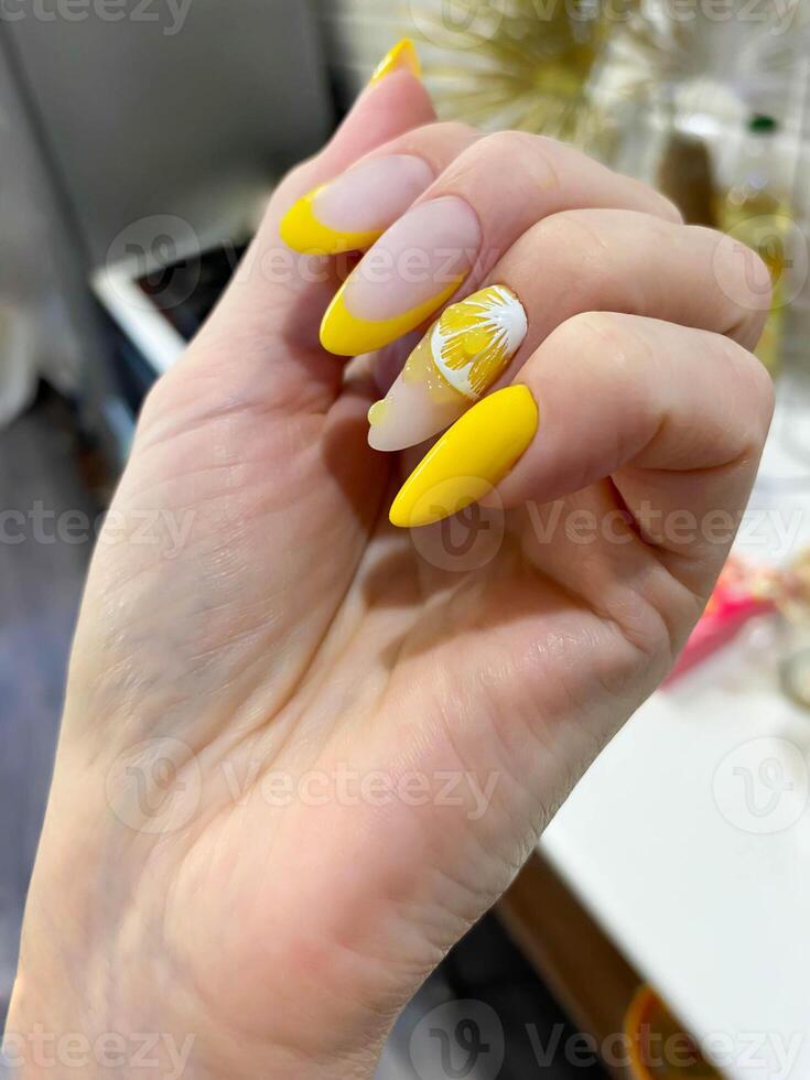 A hand with a beautiful yellow lemon manicure. photo