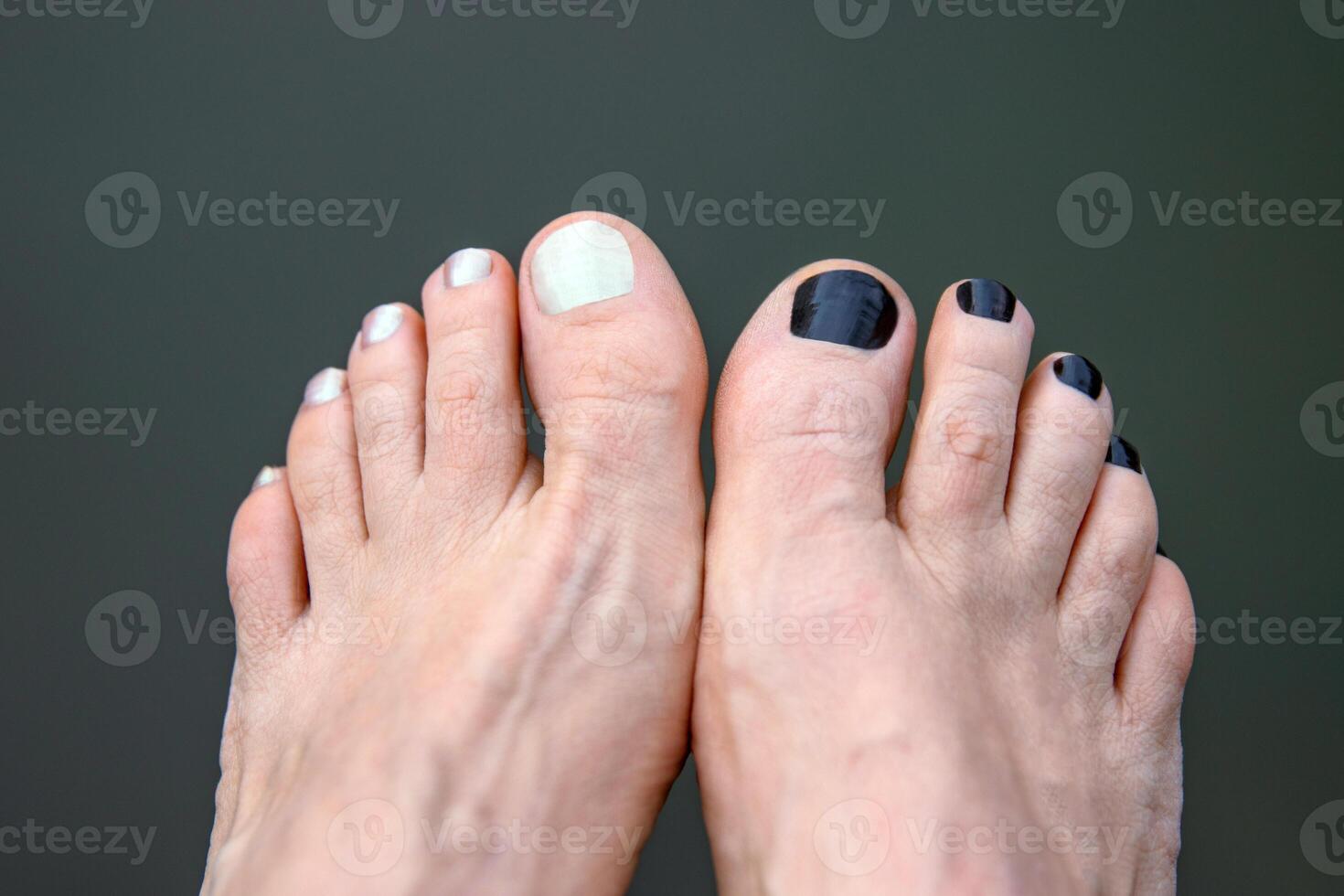 Bare feet with black and white painted toenails resting near a body of water. Two feet with contrasting nail polish, symbolizing individuality, personal style and relaxation. Copy space 02 photo