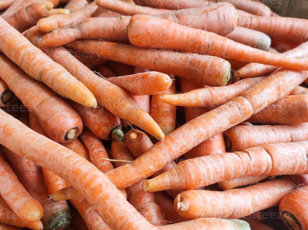 Group of fresh carrots stacked. Vegetable Backgrounds sold in traditional market shelf. Orange and tiny carrot. Texture and details. Vegetable themes wallpaper. Organic carrots background photo
