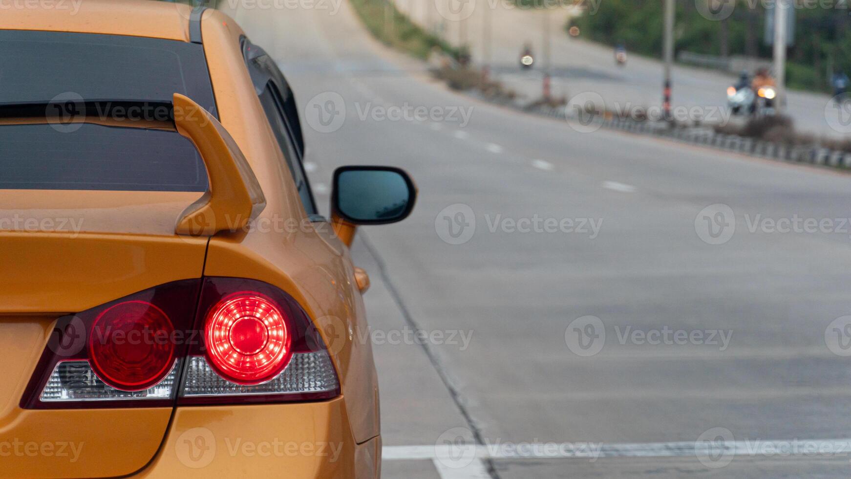 Rear side of orange car with turn brake light. Stop or prapre for race on concrete road with line white color. Empty streets with Motorcycle on the opposite side. photo