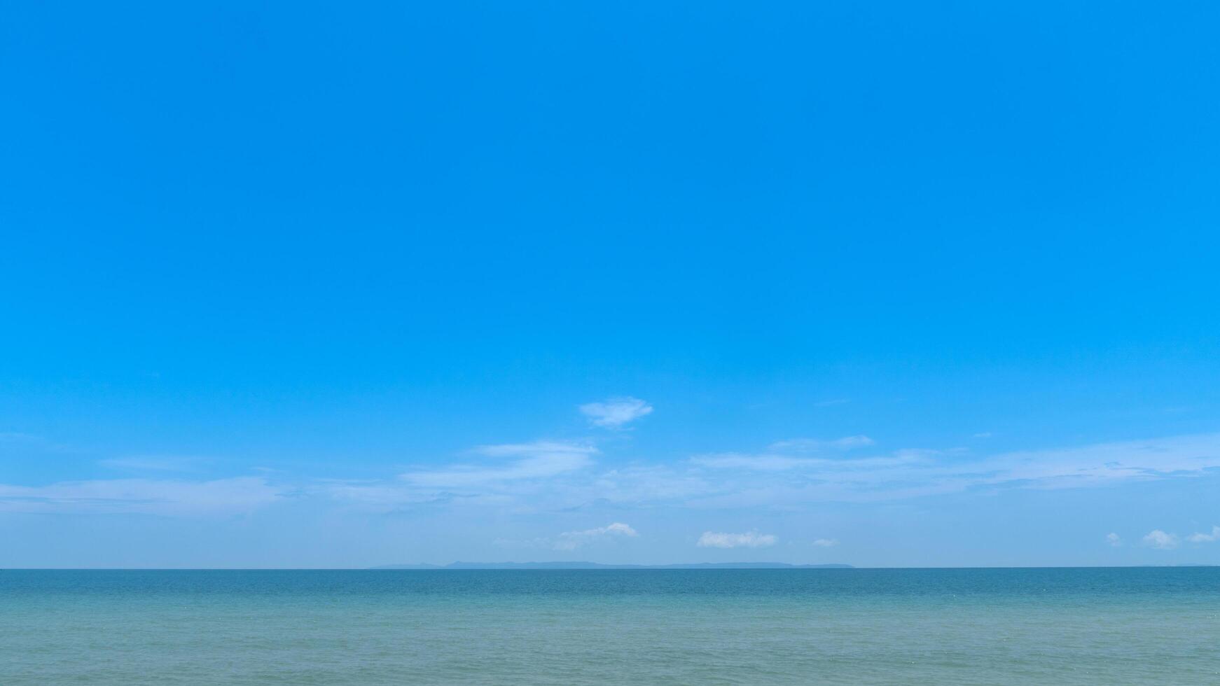 Landscape nature background of bright blue sky with a few wispy clouds over a calm light turquoise sea. Horizon line is distinct suggesting a peaceful day. photo