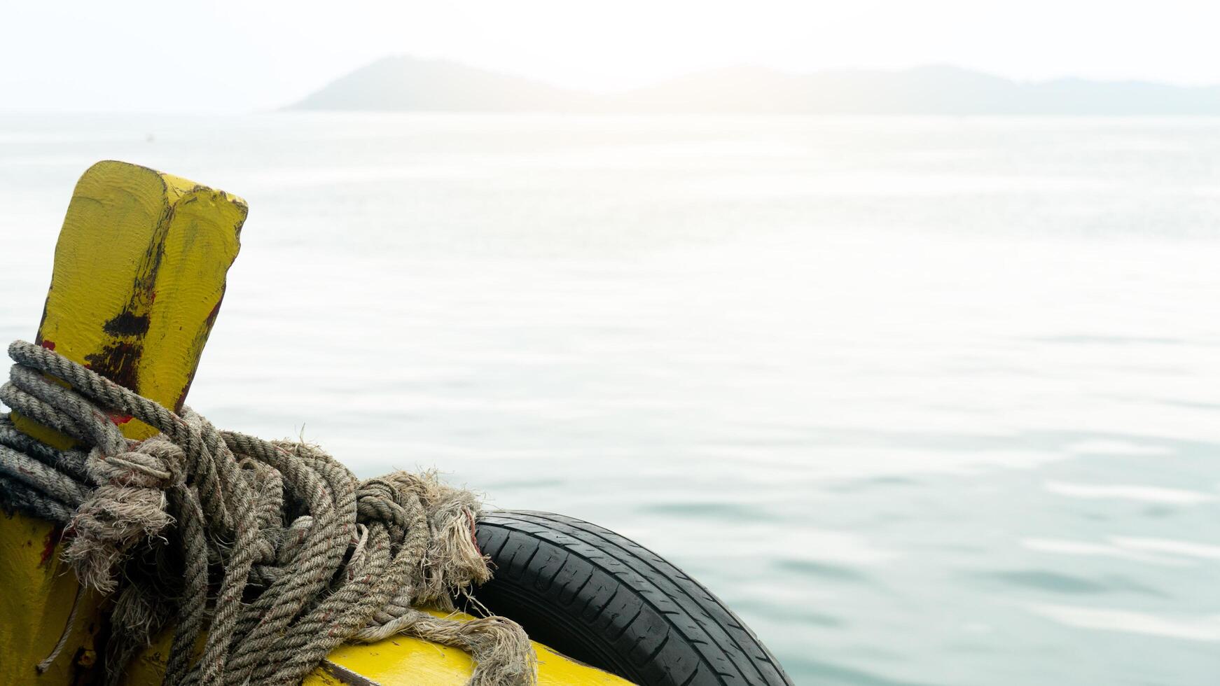 Head of a fishing boat painted in yellow on the sea. Against the background of the bright light of the sea floor and the bright sky. photo
