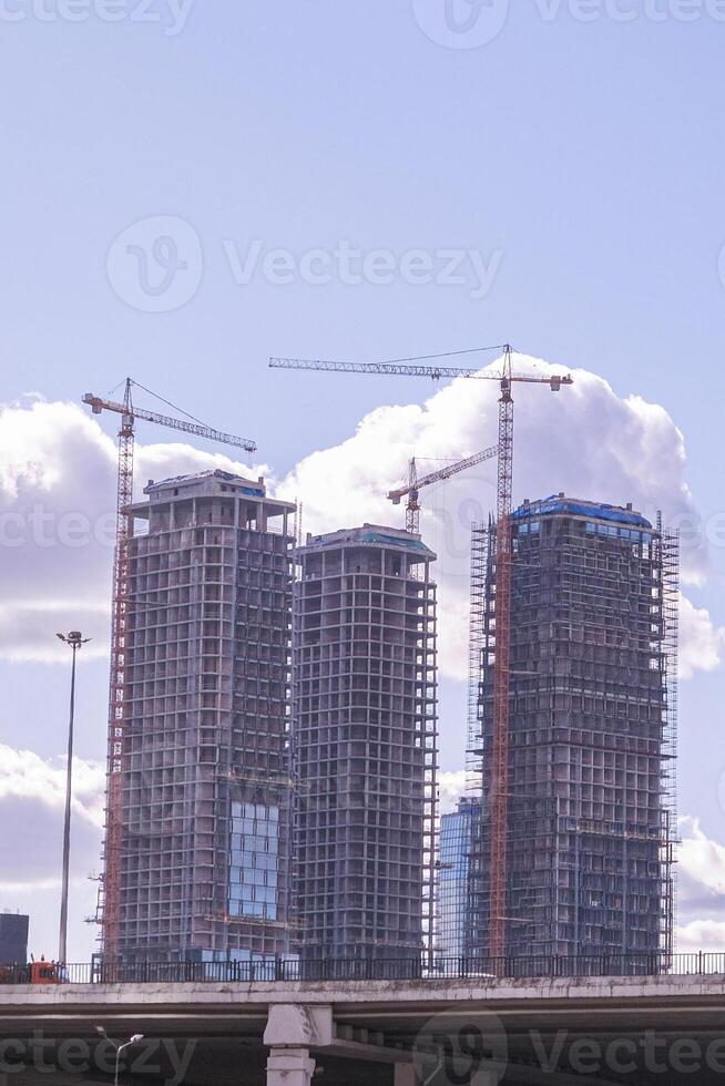 A group of cranes are working on a building under construction photo