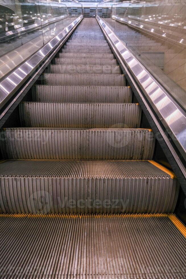 The escalator is empty and has a yellow stripe photo