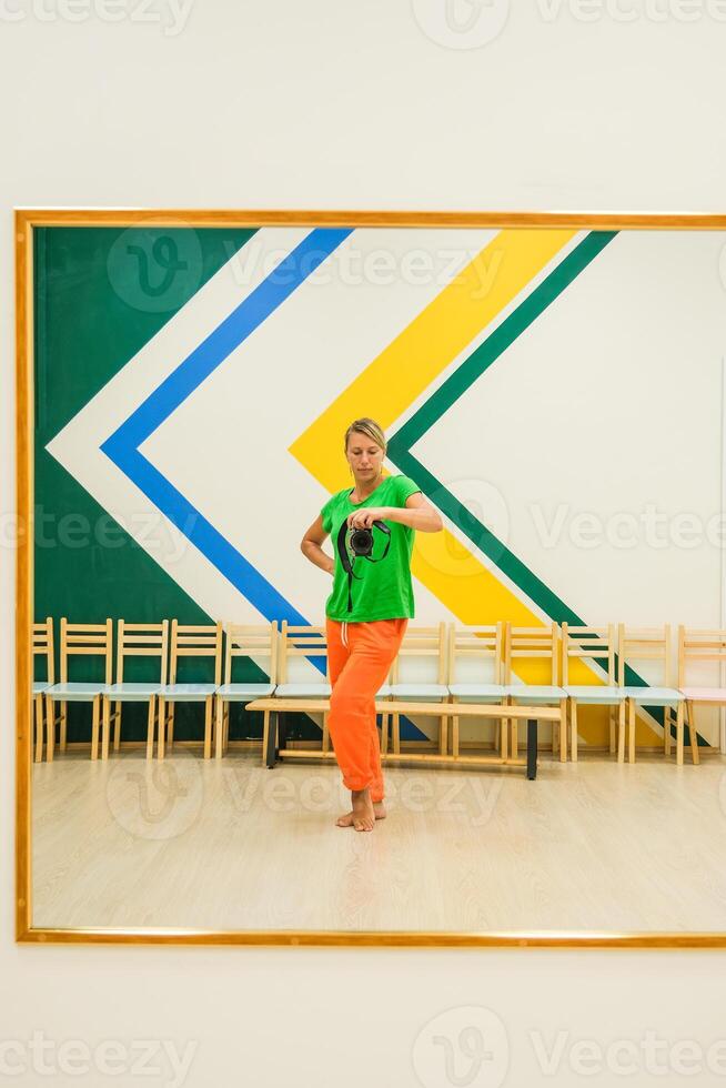 A woman in a green shirt is standing in front of a mirror photo