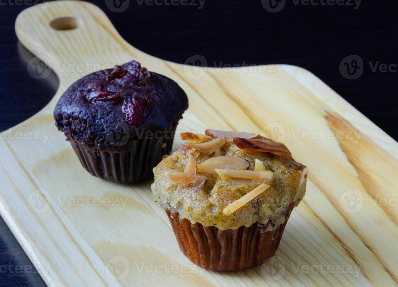 Banana cupcake and chocolate muffin on wooden tray photo