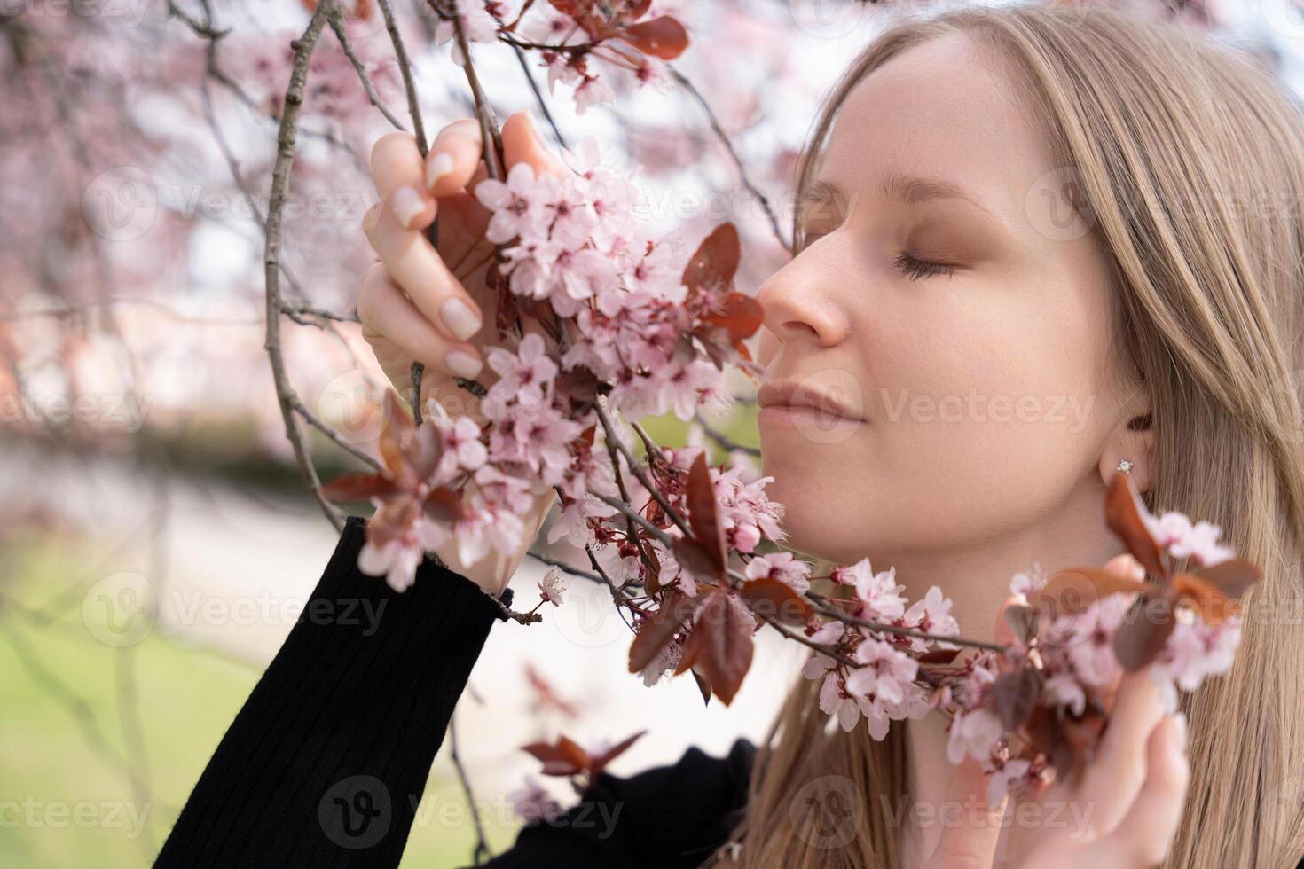 Young woman enjoying cherry blossoms in Pragues spring garden with eyes closed photo
