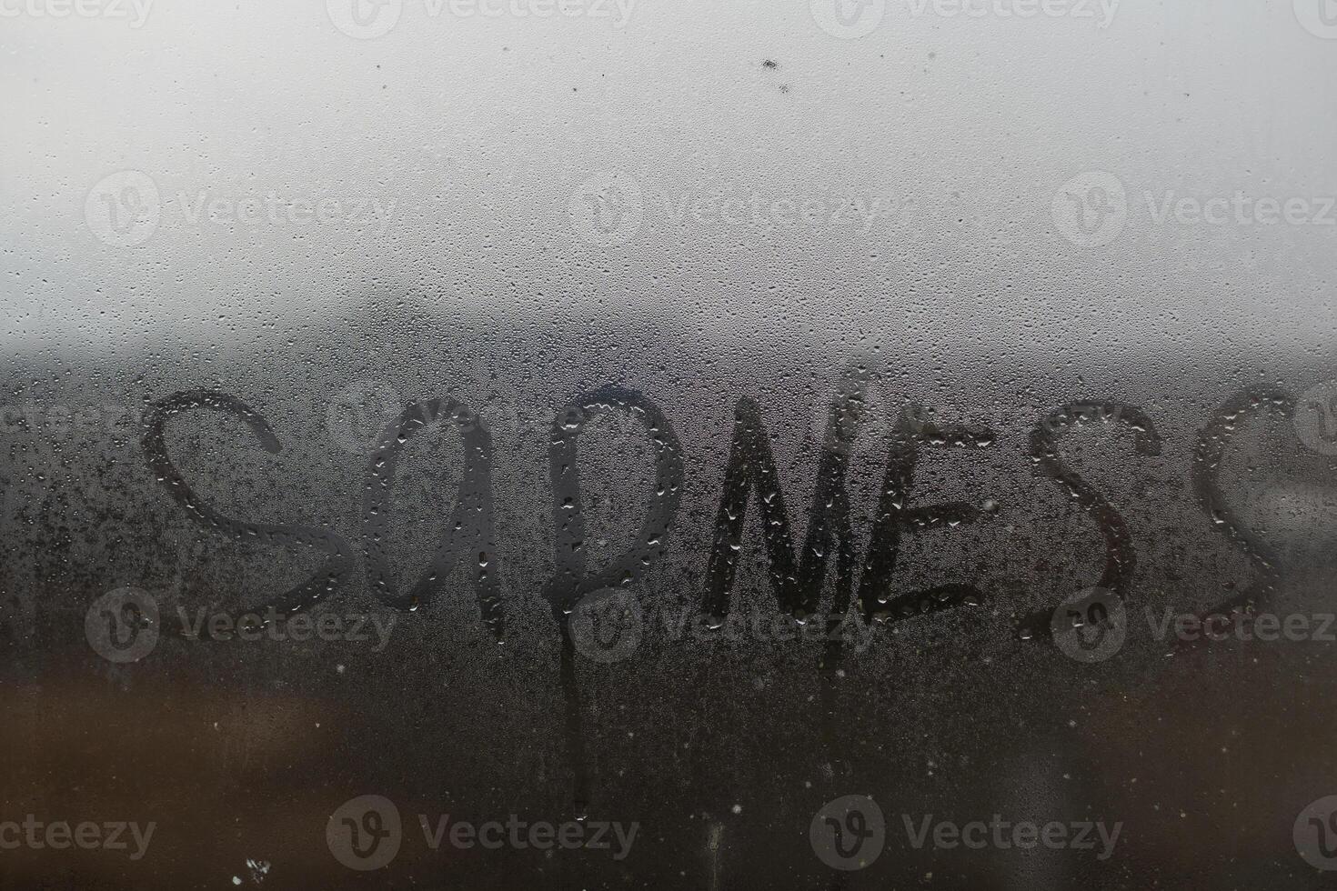 The inscription sadness on the wet window. photo