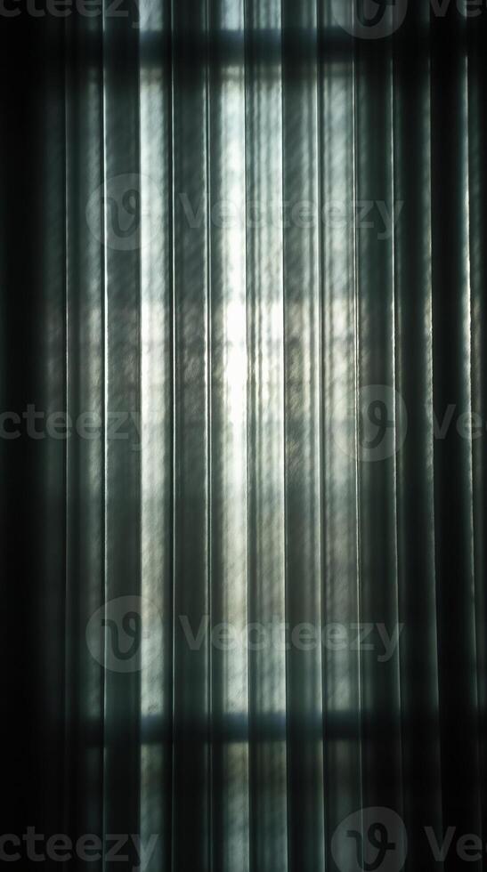 Dark sheer curtain folds backlit by bright window light photo