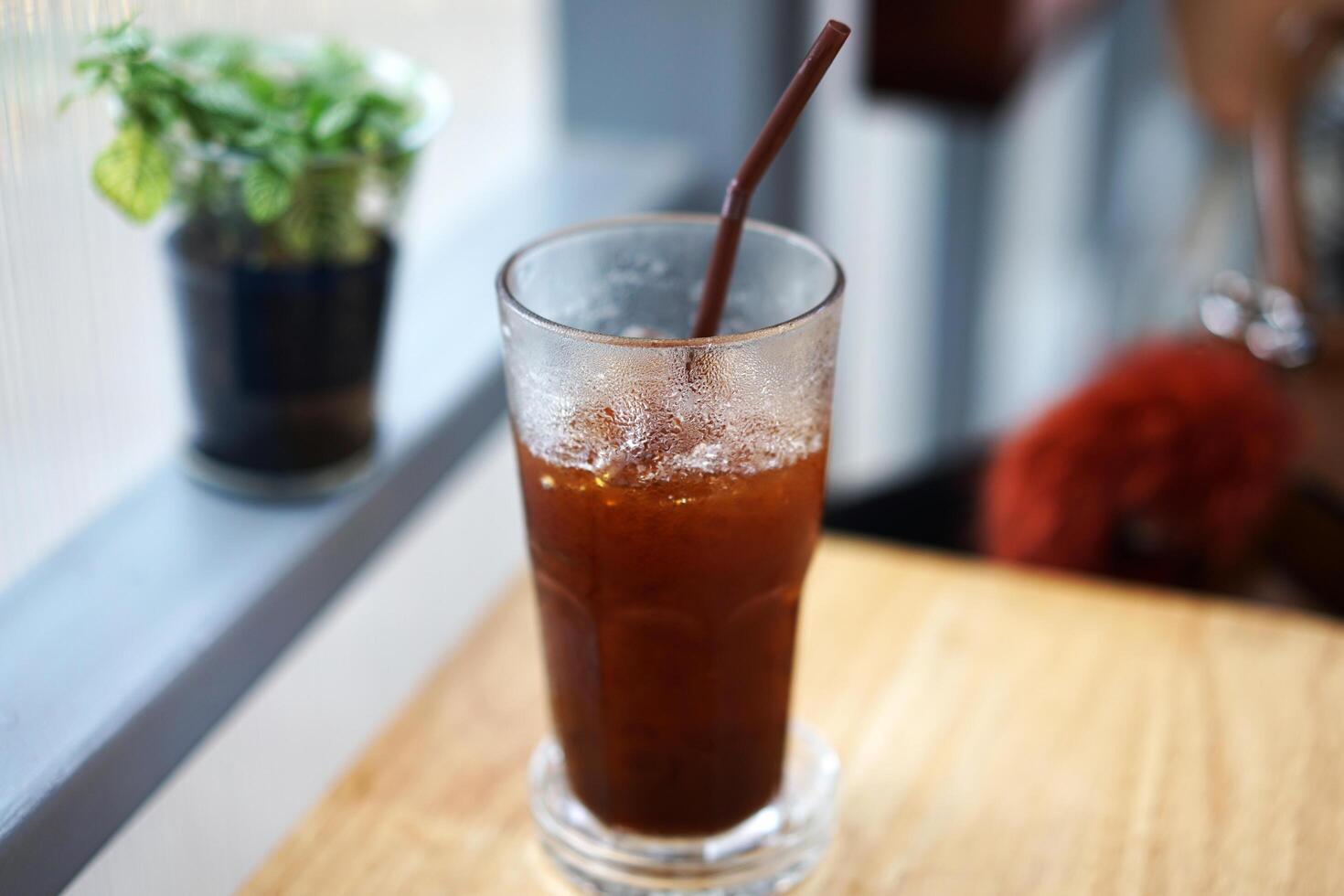 Close up glass of iced Americano black coffee on wooden table photo